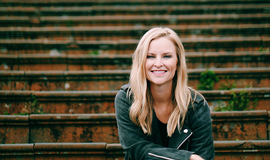 Chica rubia sonriendo sentada en unas escaleras